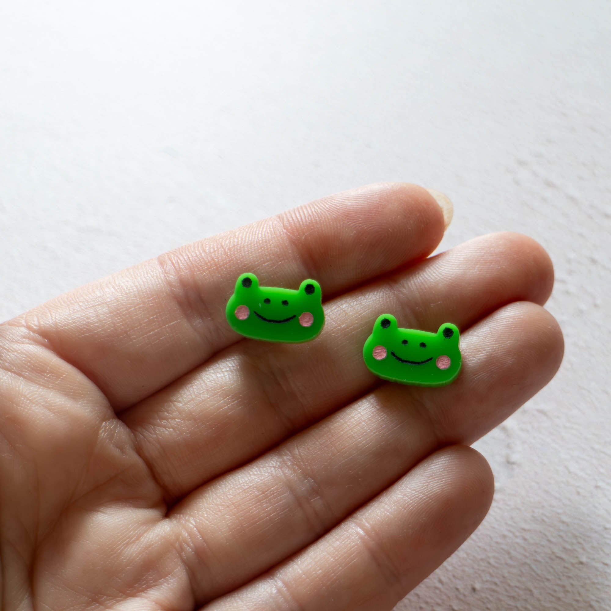 green frog face earrings with rosy pink cheeks and smiling face