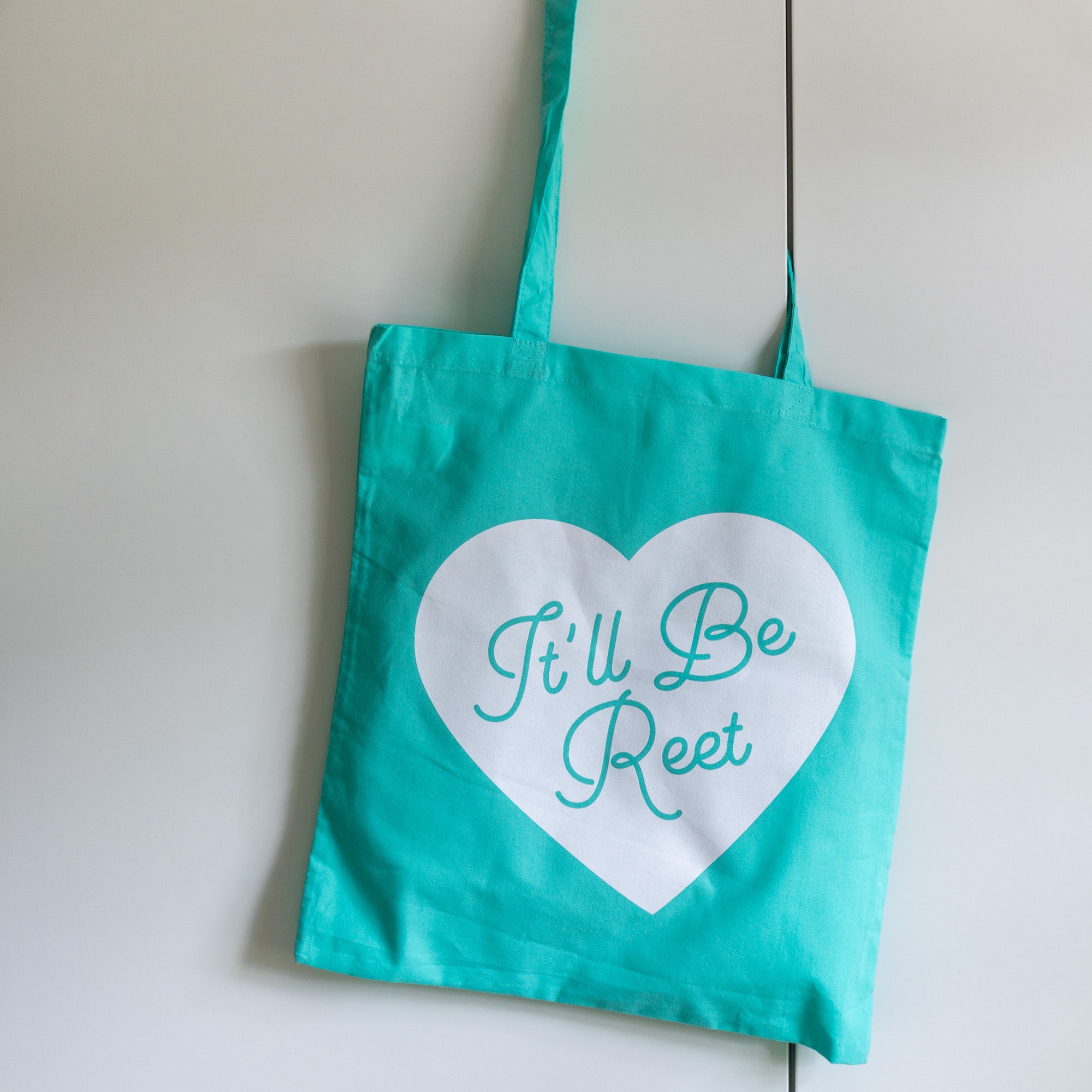 blue tote bag with white heart and It'll be reet printed slogan